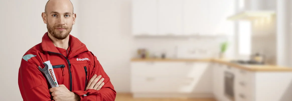 Person in Arbeitskleidung mit Schraubenschlüssel