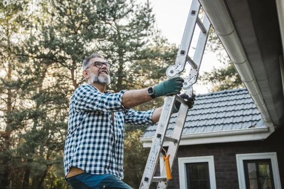 Person stellt Leiter an Hauswand