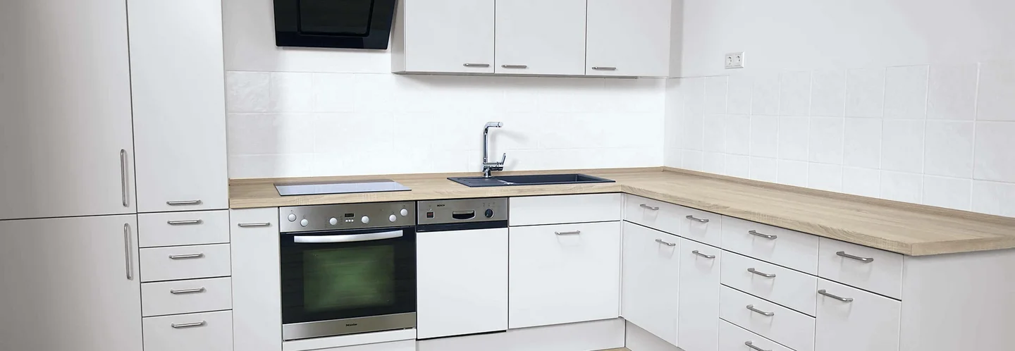Moderne Küche mit weißen Schränken und Holzarbeitsplatte.