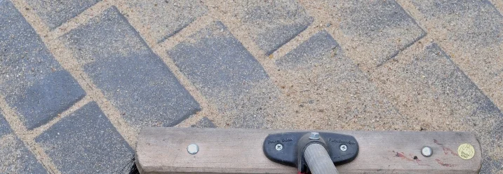 Besen fegt Sand von Pflastersteinen