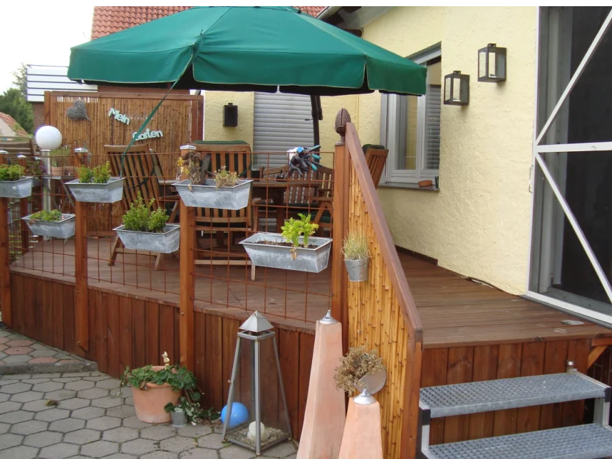 Holzterrasse mit Sonnenschirm und Blumenkästen