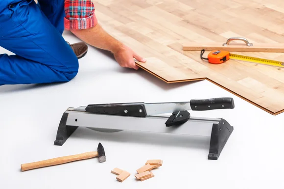 Person verlegt Laminat mit Schneidegerät