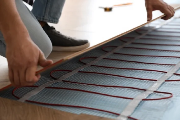 Person verlegt Heizmatten für Fußbodenheizung
