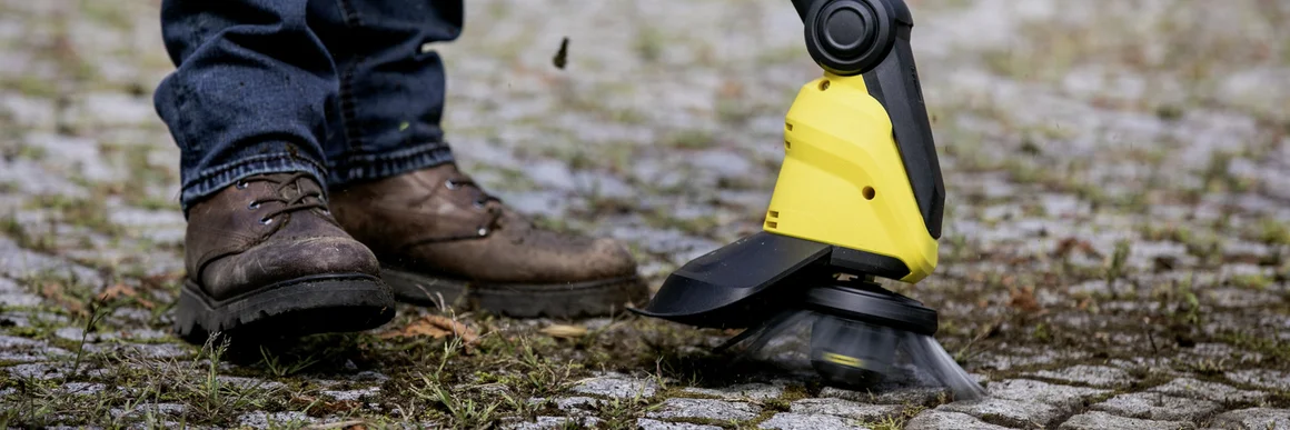 Person entfernt Unkraut mit Fugenreiniger