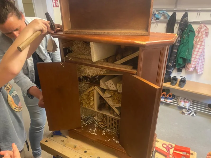 Person baut einen Holzschrank mit Hammer zusammen