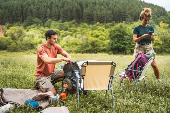 Zwei Personen packen auf einer Wiese ihre Campingausrüstung aus.