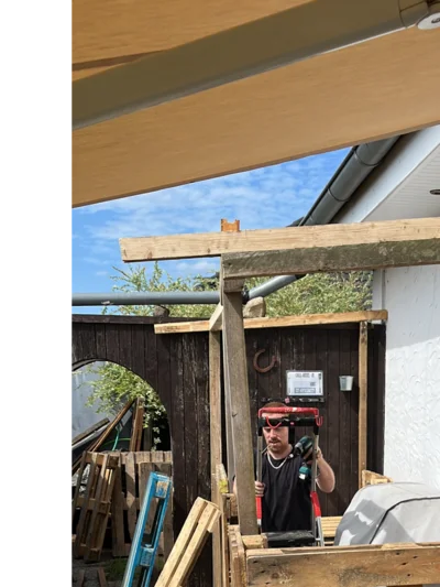 Person baut ein Gartenhaus aus Holz