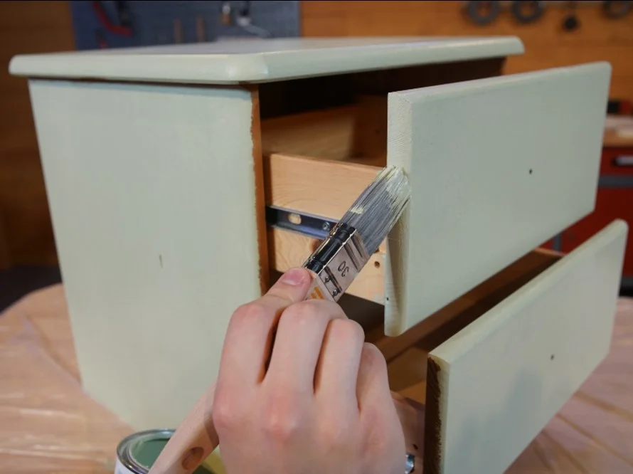 Person streicht Schublade mit Pinsel