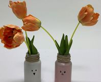Weiße und rosane Vasen mit Tiermotiven, orangene Tulpen in den Vasen