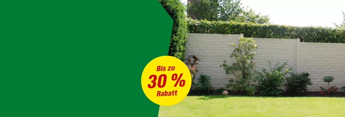 Ein Garten mit einem hellen Betonzaun und einer grünen Rasenfläche.