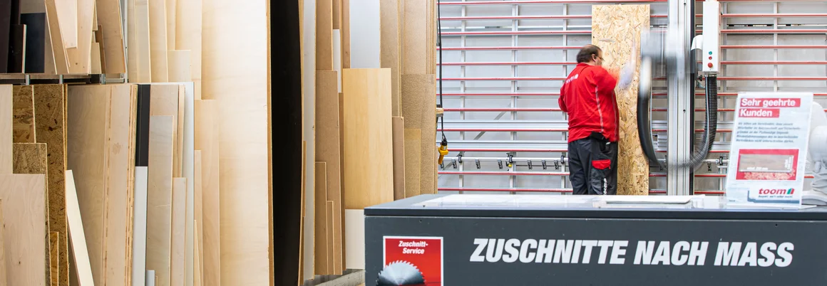 Person schiebt Holzplatte in eine große Tischkreissäge