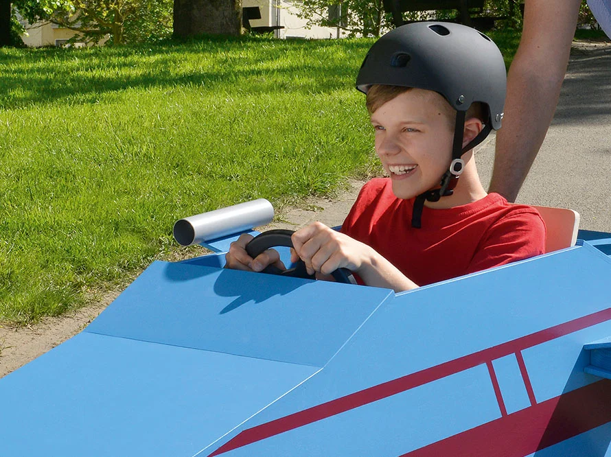 Kind mit Helm fährt Seifenkiste