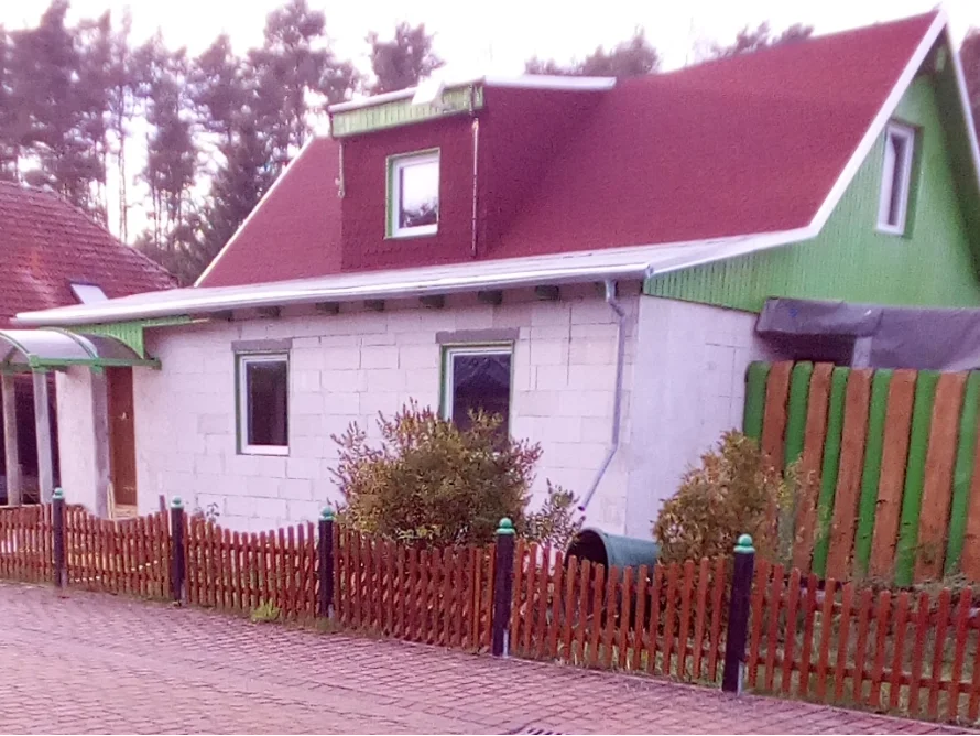 Haus mit rotem Dach und Holzzaun