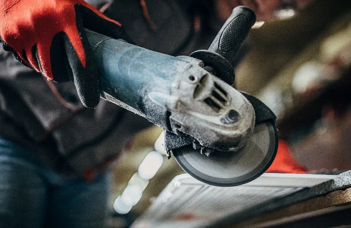 Person schneidet mit einem Winkelschleifer