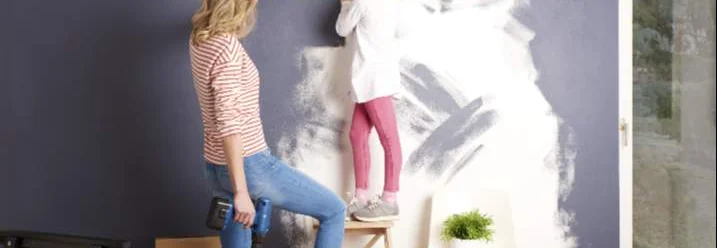 Zwei Personen messen eine Wand mit einem Zollstock aus.