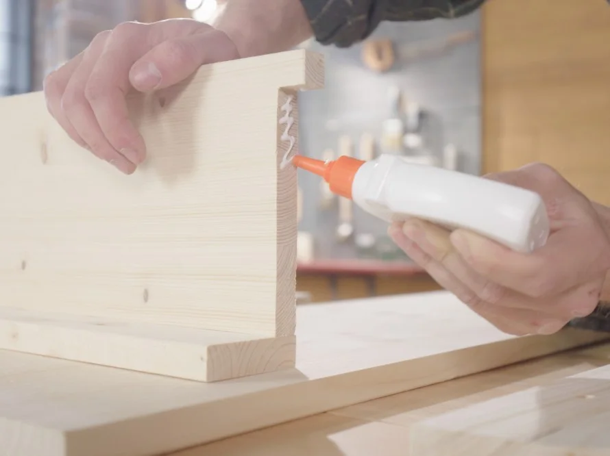 Person verklebt Holz mit Klebstoff