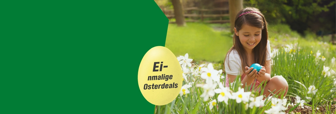 Ein Kind hält ein blaues Osterei in den Händen auf einer Blumenwiese.