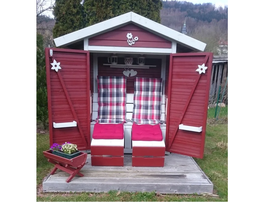 Rot gestrichenes Gartenhaus mit Sitzgelegenheit