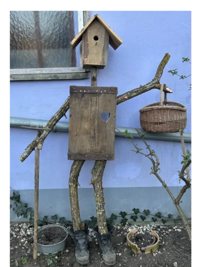 Vogelscheuche aus Holz mit Vogelhaus als Kopf.