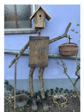 Vogelscheuche aus Holz mit Vogelhaus als Kopf.