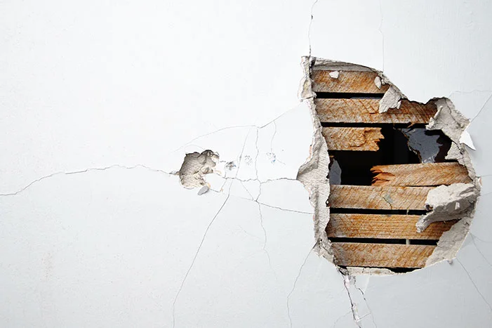 Loch in einer weißen Wand mit sichtbaren Holzlatten