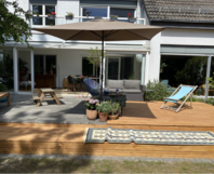 Holzterrasse mit Sonnenschirm und Gartenmöbeln