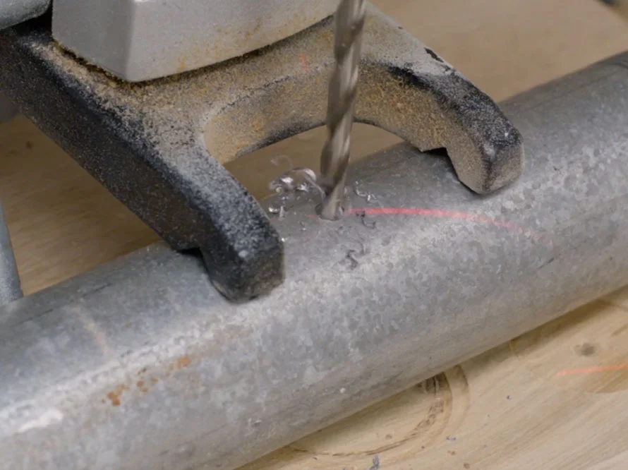 Bohrer bohrt Loch in Metallrohr