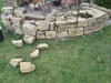 Eine runde Trockenmauer aus Natursteinen wird im Garten gebaut.
