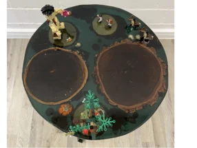 Runder Tisch mit Figuren und Bäumen