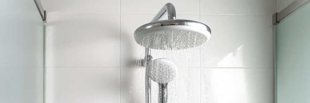 Ein verchromter Regenduschkopf, aus dem Wasser läuft.