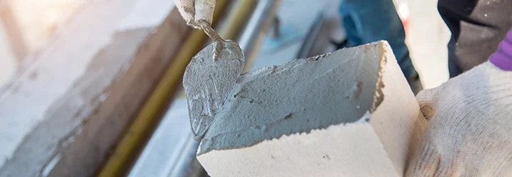 Person trägt Mörtel mit Kelle auf