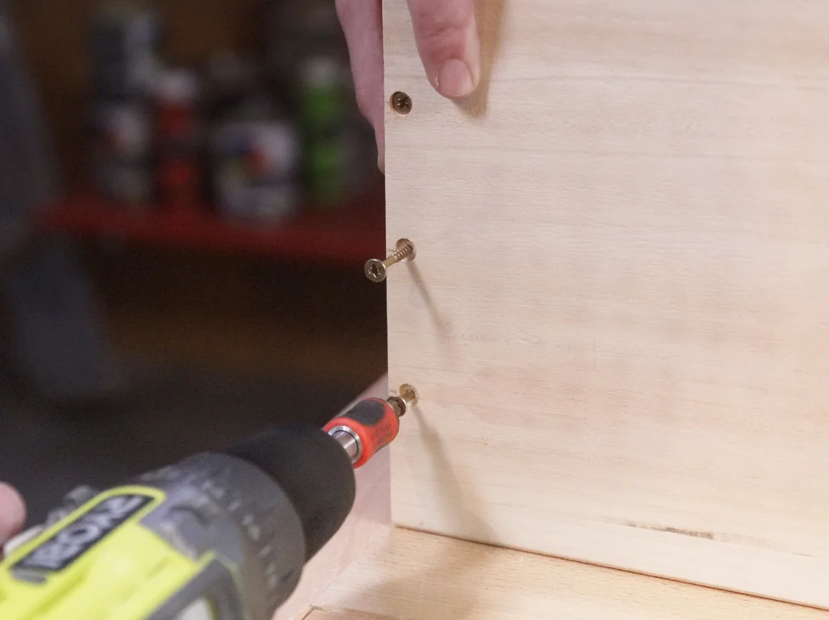 Person schraubt Holzplatte fest