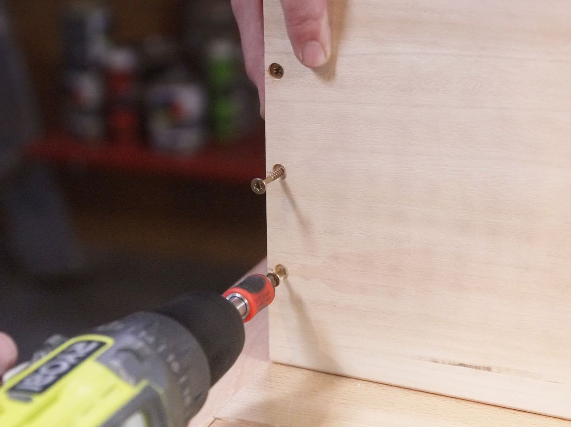 Person schraubt Holzplatte fest