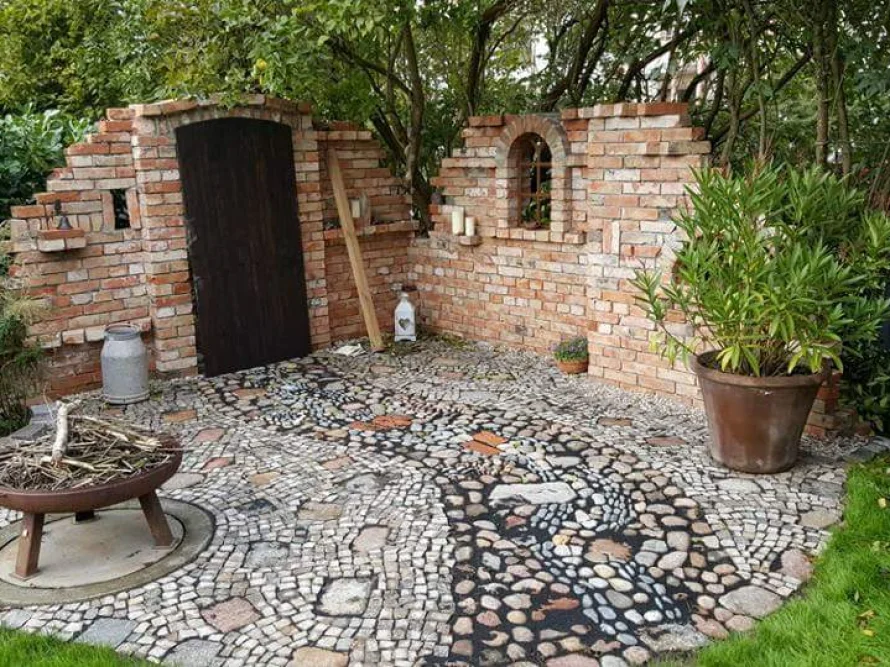 Gepflasterter Sitzplatz mit Backsteinmauer im Garten