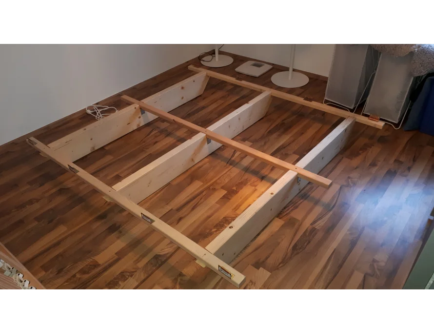 Holzrahmen eines Bettes auf einem Parkettboden
