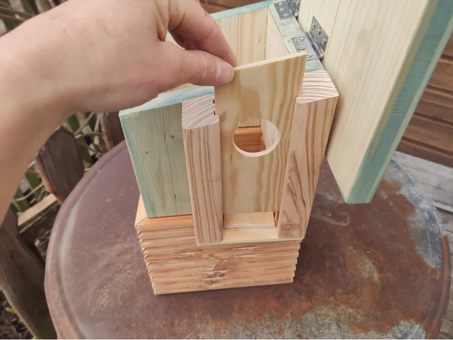 Person baut ein Vogelhaus aus Holz zusammen