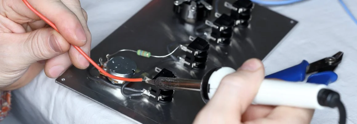 Eine Person lötet mit einem Lötkolben an einer Platine.