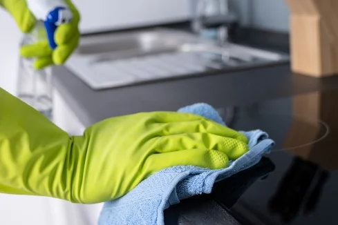 Person reinigt Herd mit Lappen