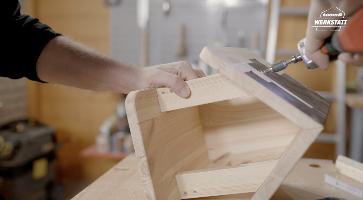 Person verschraubt Holzteile mit Akkuschrauber