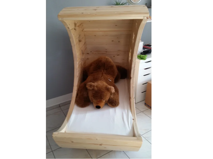 Holzbett in Form einer Wiege mit Teddybär