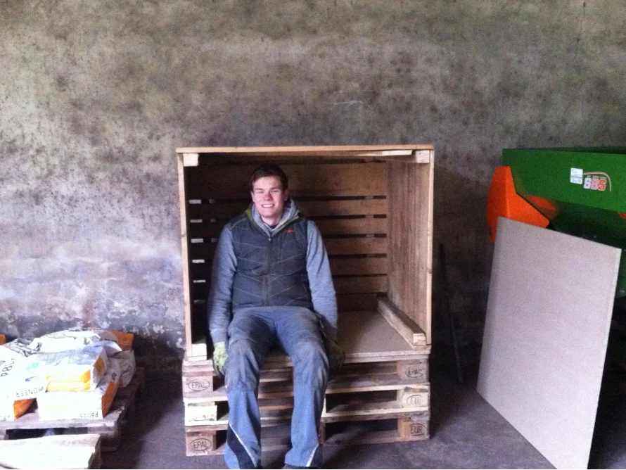 Person sitzt in einem Rahmen aus Holzpaletten