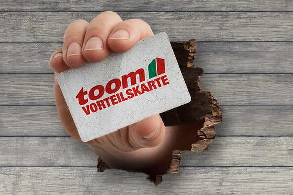 Hand hält Kundenkarte durch Holzwand