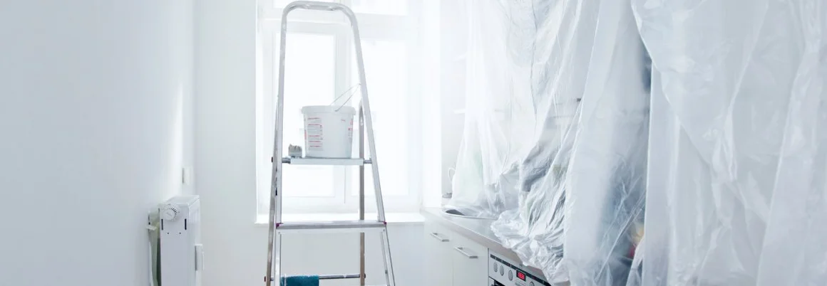 Eine Leiter mit Farbeimer steht in einem Raum, der renoviert wird.