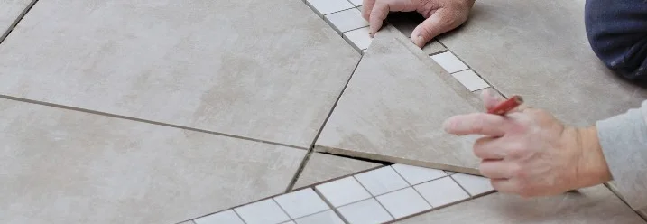 Person verlegt Fliesen mit Bleistift