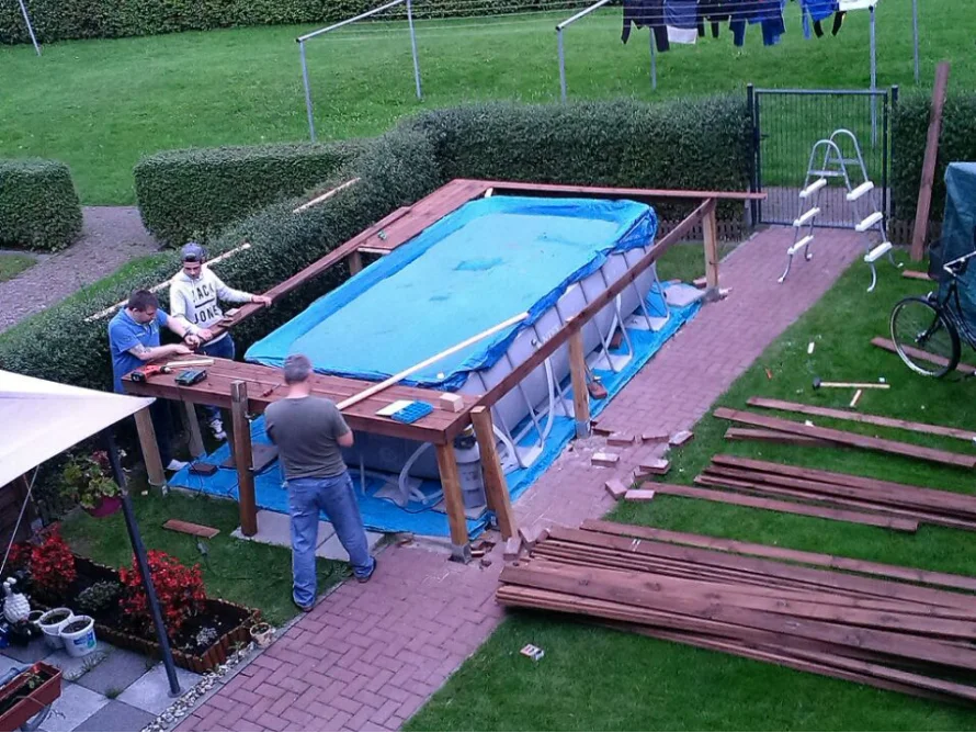 Drei Personen bauen einen Pool im Garten auf