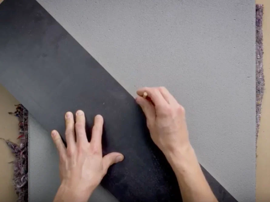 Zwei Hände zeichnen mit einem Stift auf eine graue Fläche