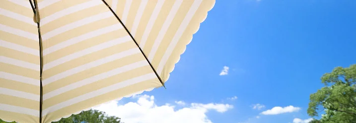 Gelb-weißer Sonnenschirm über grüner Wiese