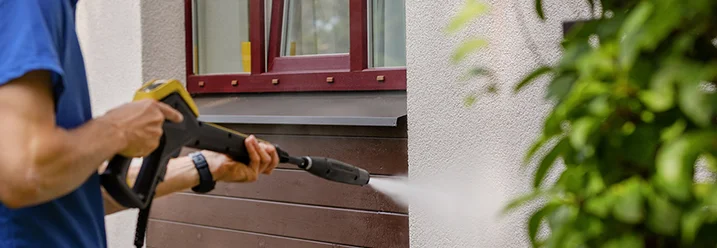 Person reinigt Fassade mit Hochdruckreiniger