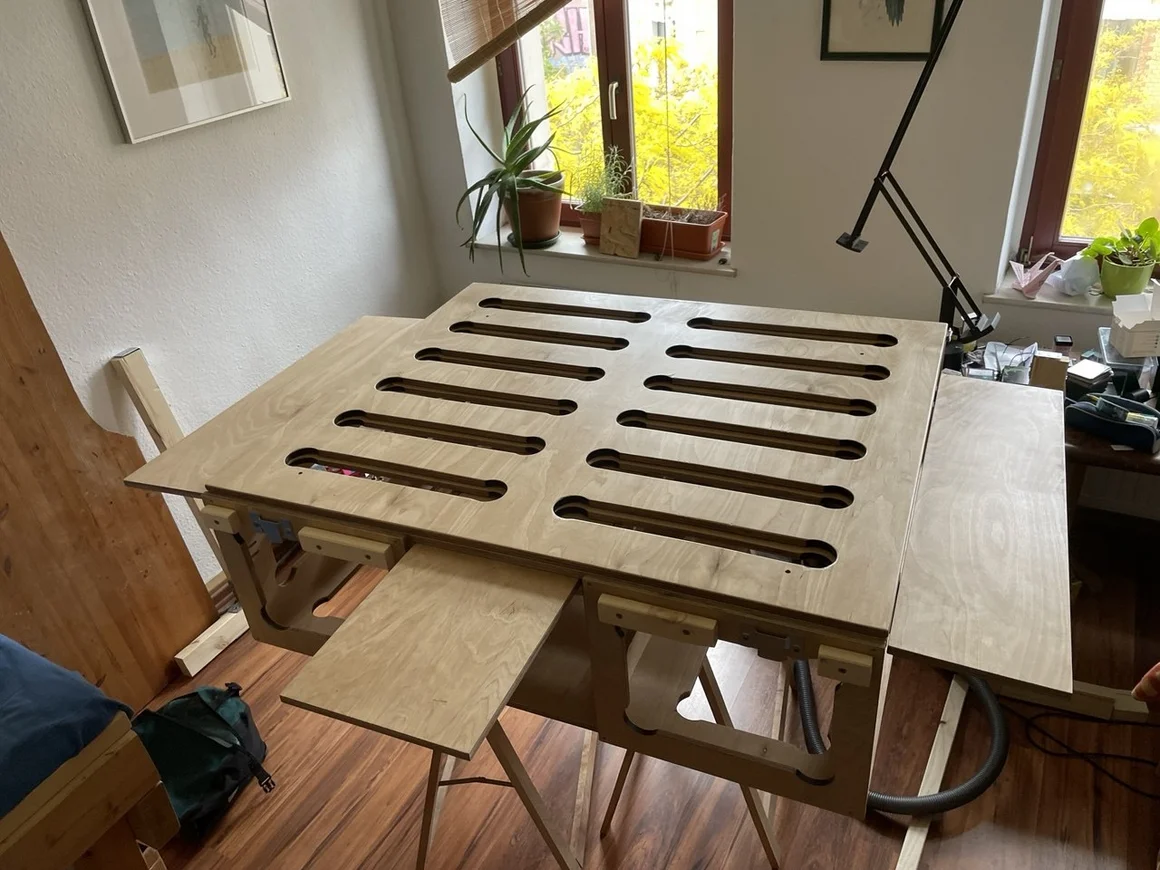 Ein selbstgebauter, ausziehbarer Multifunktionstisch aus hellem Holz mit einer Lochrasterplatte.