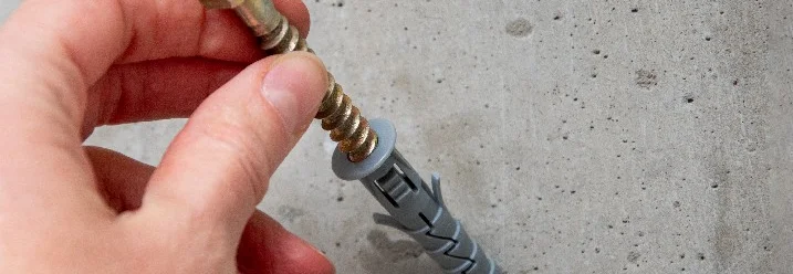 Hand hält Dübel und Schraube